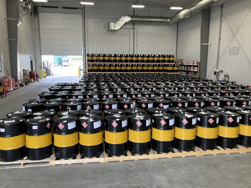 Rows of black and yellow 205-litre fuel drums on pallets inside the drumming facility